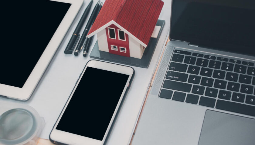 telephone près d'une maquette de maison et d'un ordinateir