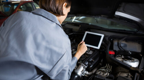une femme utilise un écran de diagnostic pour réparer une voiture