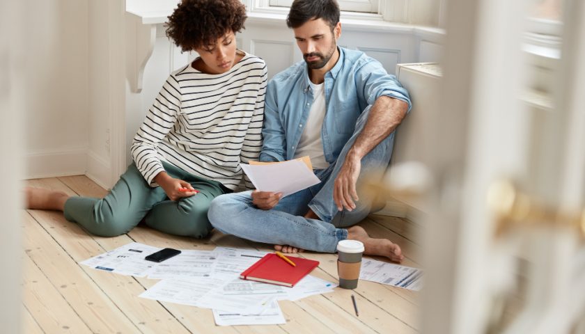 un jeune couple assis dans leur appartement et regardant des papiers