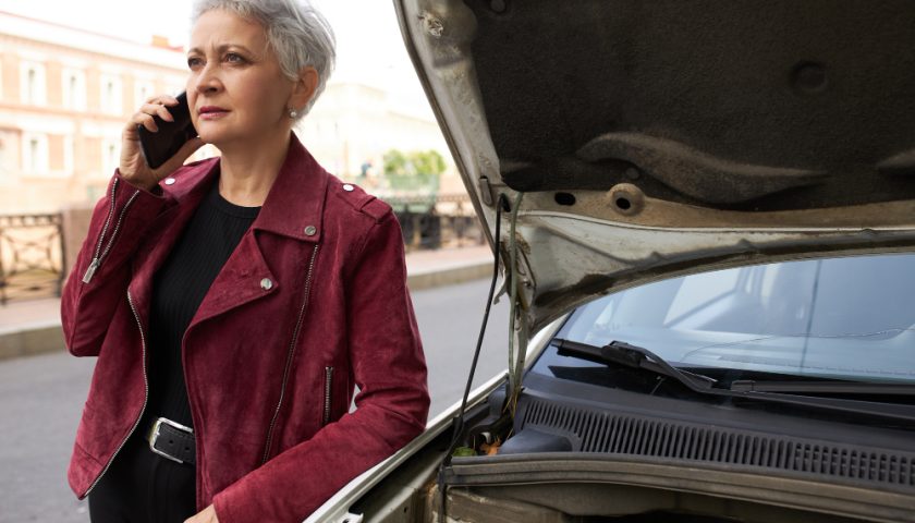 une femme devant sa voiture en panne